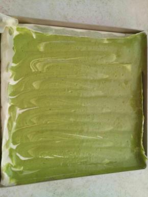 把抹茶糊装入裱花袋一行一行挤到原味糊的上面。