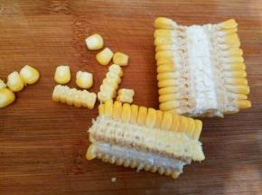  压熟的玉米，对半切开，刀顺着一边，就可以整齐的把玉米粒切下来了，