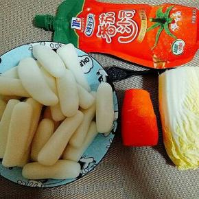 准备食材。年糕洗干净。胡萝卜去皮切丝，娃娃菜洗干净切丝。