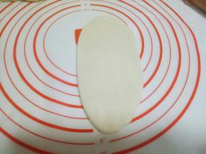 取一小块面团，用擀面杖擀成长舌状。