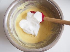 蛋白中加入几滴柠檬汁，分三次加入糖，打发至湿性发泡，取三分之一蛋白加入蛋黄糊中，切拌均匀