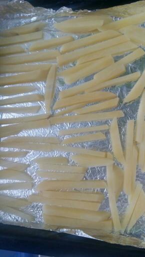 烤盘铺锡纸，上面刷油把拌好的薯条铺在烤盘上