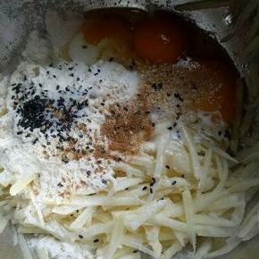 准备个大口的容器，加入牛奶，鸡蛋，土豆丝，面粉，十三香，盐，黑白芝麻，葱花。混合