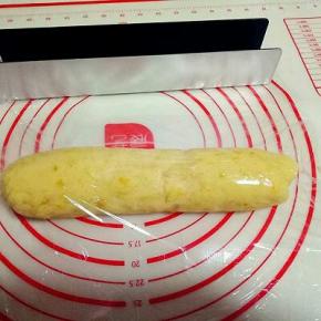 揉好的面团用保鲜膜包好，按压做出磨具的长方形。