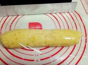 揉好的面团用保鲜膜包好，按压做出磨具的长方形。