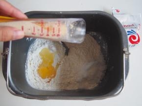将面粉、奶粉、糖、盐、鸡蛋放到面包机桶中，在一侧放入蛋液，在另一侧放入酵母