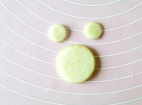 首先取一块西瓜皮，去掉红色的和绿色的部分，用圆形模具分别刻出青蛙的脸部和耳朵。