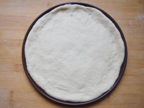 将面团擀成圆形饼状，均匀铺在披萨盘上，将边缘整理整齐