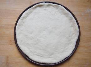 将面团擀成圆形饼状，均匀铺在披萨盘上，将边缘整理整齐