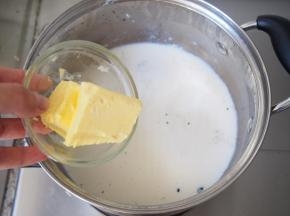 将牛奶中的香草荚过滤出来，加入黄油、朗姆酒再次小火煮开