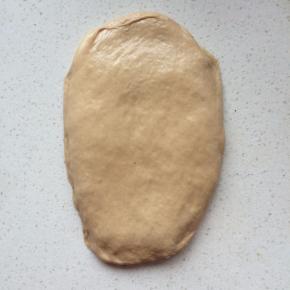 9、	静置好后，将面团光面向上，用擀面杖轻轻擀开