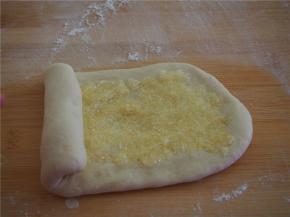 取其中的一块擀成椭圆形，放入三分之一的椰蓉馅料，从一端卷起