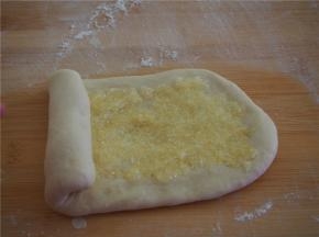 取其中的一块擀成椭圆形，放入三分之一的椰蓉馅料，从一端卷起