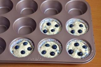 将面糊舀入纸托中，上面各放四颗蓝莓。