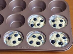 将面糊舀入纸托中，上面各放四颗蓝莓。