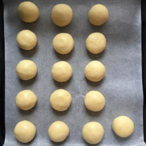 取出，这时候预热烤箱，170度，上下火，然后把芝士面团分成每个20g左右，揉圆成球状，放入垫了油纸的烤盘上