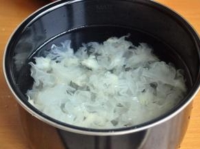 将银耳黄色的根部去掉，撕成小朵，加入适量水。