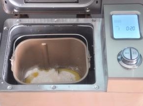 面包桶内依次加入水、牛奶，倒入面粉，尽量让面粉覆盖整个水面，靠近面包桶一角放盐、另一角放糖。在面粉上挖个坑，把酵母放入小坑内，确保酵母不与水和盐接触，倒入橄榄油，面包桶放入到面包机内，顺时针旋转，卡紧面包桶。选择和面程度，揉面20分钟，启动程序。