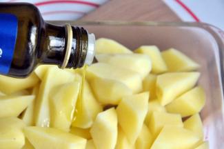 将土豆捞出沥干水分后放入一个玻璃盒，倒入适量橄榄油拌匀。