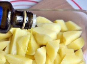 将土豆捞出沥干水分后放入一个玻璃盒，倒入适量橄榄油拌匀。