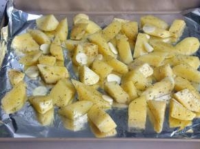 在烤盘中垫一张锡纸，方便后期清洁，将土豆块均匀的放置烤盘中，放入蒜片。