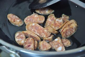 锅中倒入少许油，放入香肠片，煸炒至出油。