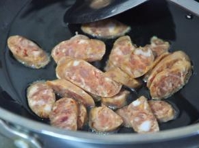 锅中倒入少许油，放入香肠片，煸炒至出油。