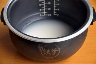 电饭煲中放入洗净的米和水，水量高出大米一指。