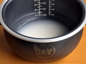 电饭煲中放入洗净的米和水，水量高出大米一指。