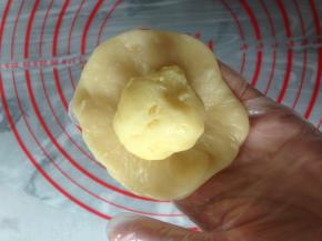 再擀成中间厚四周薄的圆形面皮，中间放入绿豆馅