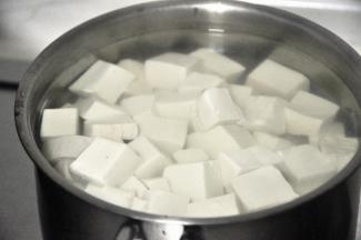 . 倒掉浸泡的水，将豆腐放入小锅中，重新换水，放1勺盐，将水烧开即可关火，捞出豆腐沥干水份备用。