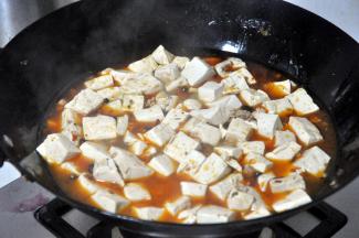 倒入豆腐，加开水盖过三分之二的豆腐，加入少量的生抽，轻轻用锅铲翻匀。
