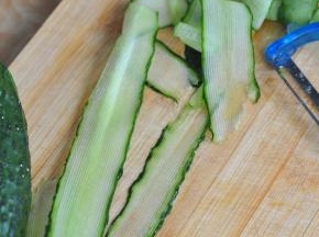 将黄瓜用削皮器削成长长的薄片。