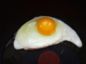 热锅热油，将鸡蛋打入平底不粘锅，煎至七八成熟，就是底部凝固，边缘有焦痕，蛋黄表面薄薄一层稍有流动的样子