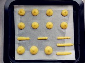 将面糊装入剪口的裱花袋中，在铺了油纸的烤盘上挤出圆形和稍细的长条形。每个泡芙之间要留出足够的膨胀距离