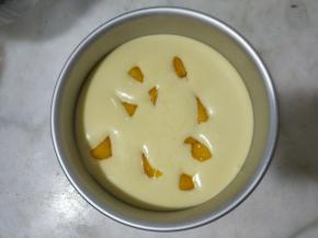 模具底部垫上油纸，将慕斯糊倒入六寸活底模具，均匀放入50克芒果肉，放入冰箱冷冻5-8分钟。