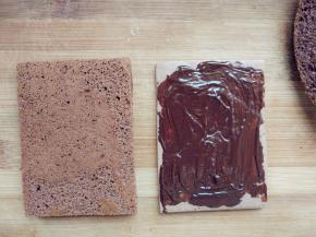 烤好的饼干取出晾凉，将蛋糕片照饼干的大小切好，在饼干上涂少许融化的黑巧克力，将薄、厚两片蛋糕片依次放在饼干上