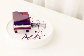 将凝固的钢琴盖放在顶部，一侧用一小块蛋糕体支撑起，另用黑巧克力在盘上画出音符即可