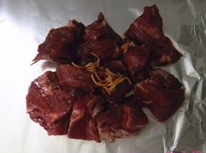 将腌好的梅花肉放在锡纸上，将腌肉的料汁倒在肉上；