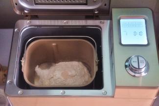 先做一个港式吐司，可以提前一晚制作好，密封保存，随吃随用。先把液体材料放入面包桶中，面粉铺在上面，对角分别上放上盐、糖、奶粉，在面粉中间挖一个小坑，放上酵母，启动面包机揉面程序10分钟。