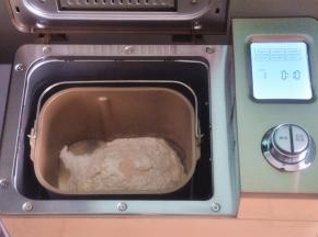 先做一个港式吐司，可以提前一晚制作好，密封保存，随吃随用。先把液体材料放入面包桶中，面粉铺在上面，对角分别上放上盐、糖、奶粉，在面粉中间挖一个小坑，放上酵母，启动面包机揉面程序10分钟。