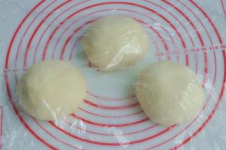 将面团取出，按揉排气后面团均分成三团，盖上保鲜膜松弛15分钟。