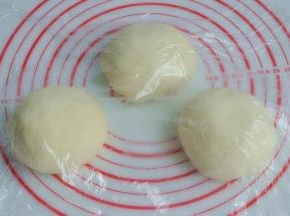 将面团取出，按揉排气后面团均分成三团，盖上保鲜膜松弛15分钟。