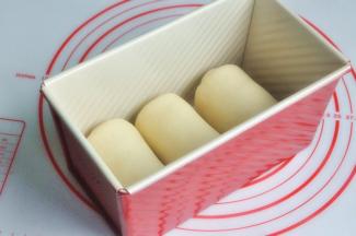 再次擀开成长条状，面团卷起，收口朝下放置，将面团放入吐司模。