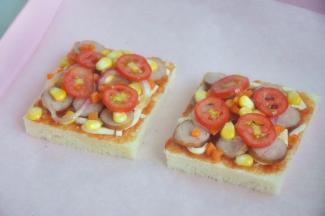 将香肠、玉米、洋葱、圣女果、胡萝卜放在吐司片上。