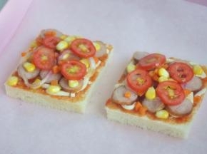 将香肠、玉米、洋葱、圣女果、胡萝卜放在吐司片上。