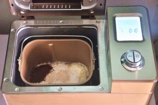 把液体材料放入面包桶中，面粉铺在上面，对角分别上放上盐、糖、可可粉，在面粉中间挖一个小坑，放上酵母，启动面包机揉面程序10分钟。