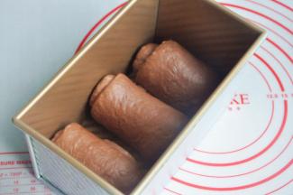 将面团擀开卷成圆筒状，3个都做同样处理，盖上保鲜膜静置15分钟左右，再次擀开成长条状，面团卷起，收口朝下放置，将面团放入吐司模。