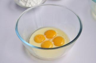 先做蛋糕胚，可以用方形的阳级模来烤戚风，再切割蛋糕片，但我觉得直接烤蛋糕片更为方便省时，先将蛋清和蛋黄分离，蛋黄盆里倒入牛奶和油，让牛奶和油充分包裹蛋黄，然后放一边备用。