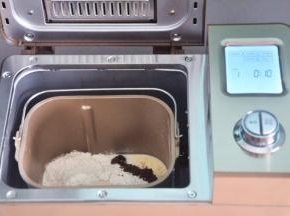 把液体材料放入面包桶中，面粉铺在上面，对角分别上放上盐、糖、奶粉，在面粉中间挖一个小坑，放上酵母，启动面包机揉面程序10分钟。